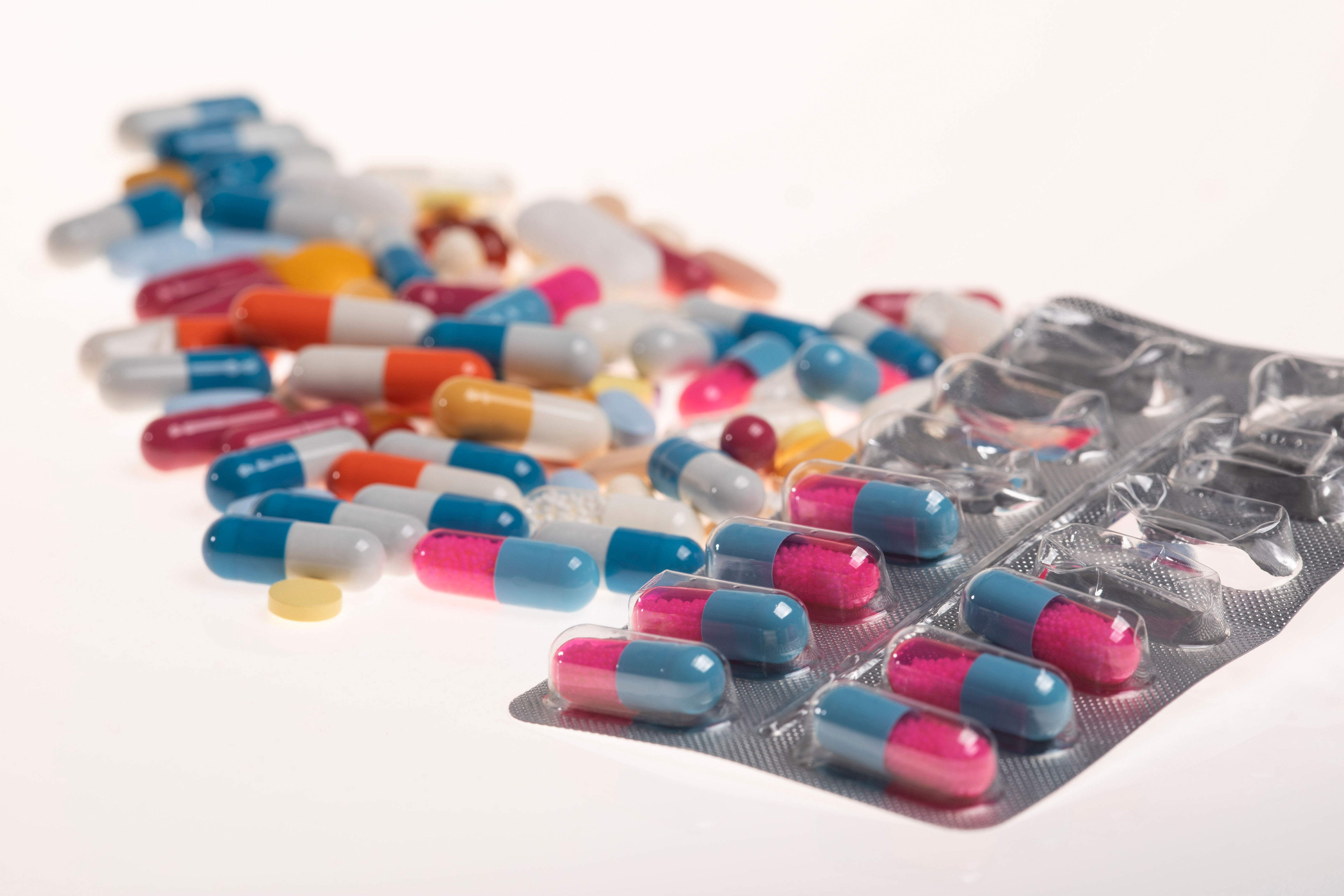 Nahaufnahme vieler, bunter Tabletten in verschiedenen Farben auf einer hellen Unterfläche