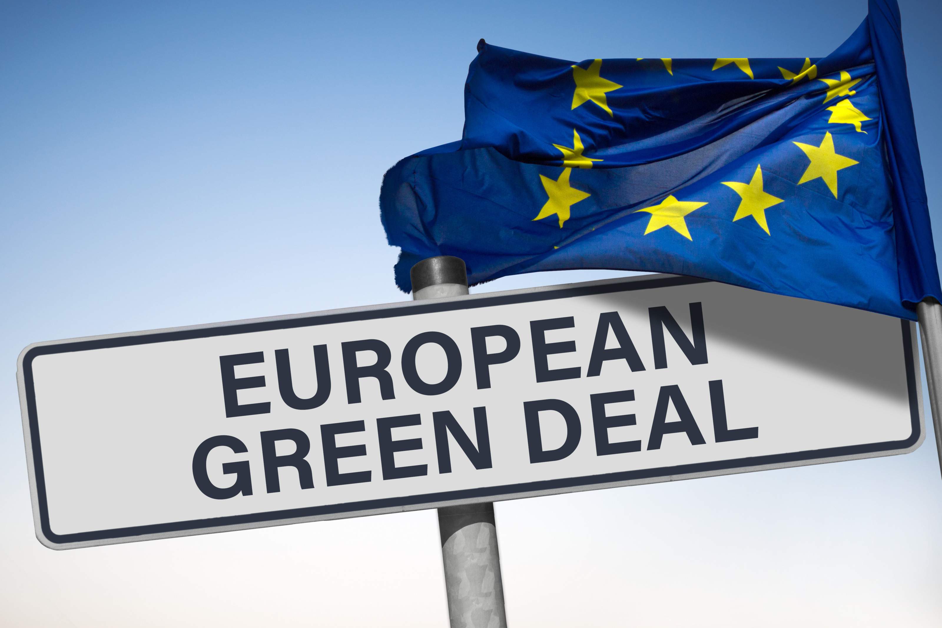 Schuld mit Schriftzug European Green Deal, darüber im Wind wehende Europaflagge