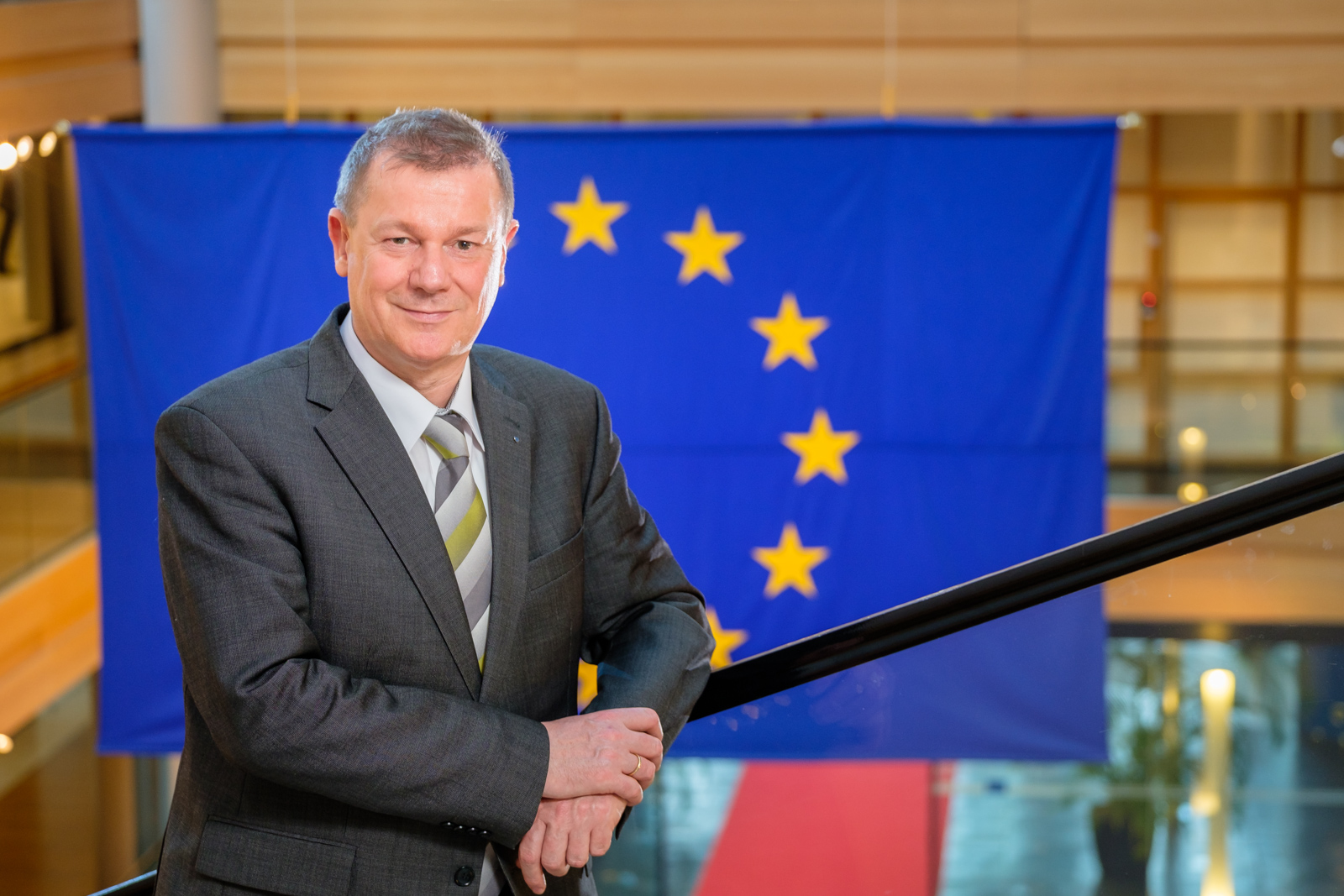Markus Pieper an ein Geländer gelehnt vor der EU-Flagge