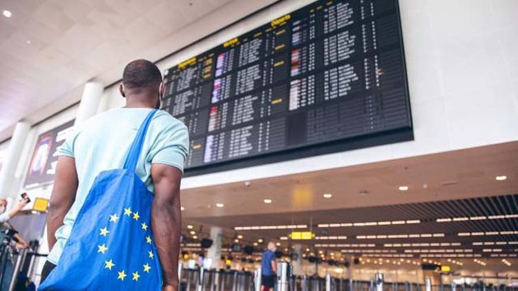 Mann mit Europa-Beutel schaut auf Flug-Infos