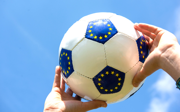 Fußball mit EU-Flaggen-Muster von Händen gen Himmel gestreckt